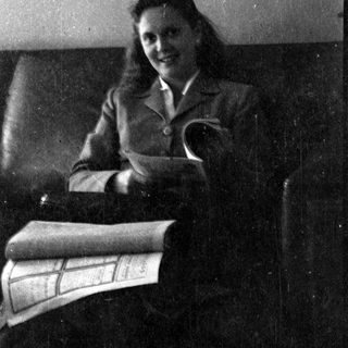 Woman in a blazer sitting on a leather sofa.