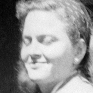 Woman in a suit standing in a vehicle doorway.
