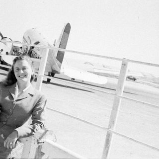 Woman posing in front of a propeller airplane.