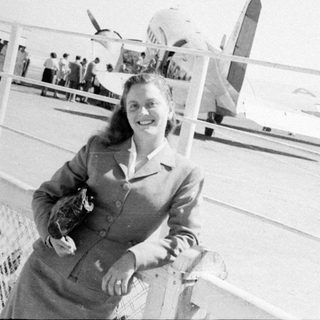 Woman posing in front of a propeller airplane.