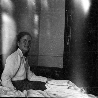 Woman sitting on a bed with heavy light leaks.