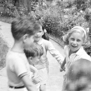 Three children on a garden path near a building.
