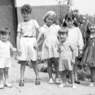 Five children posing outdoors in mid-century clothing.