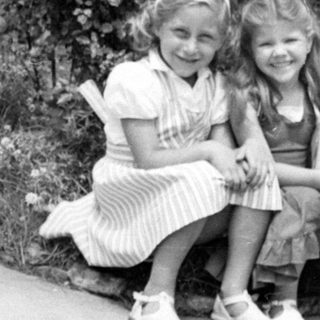 Three girls sitting in a flowering garden.