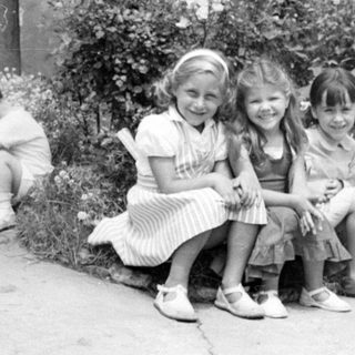 Three girls sitting in a flowering garden.