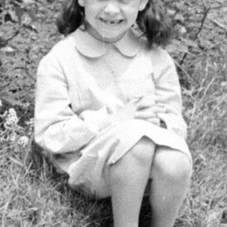 Young girl in a dress sitting in a garden.