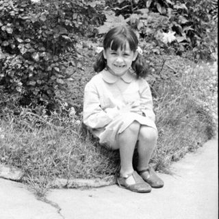 Young girl in a dress sitting in a garden.