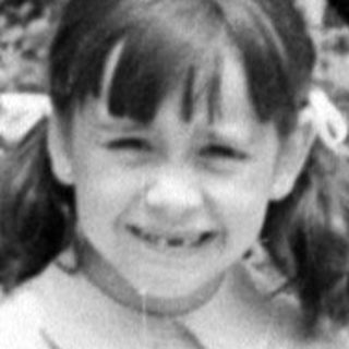 Young girl in a dress sitting in a garden.