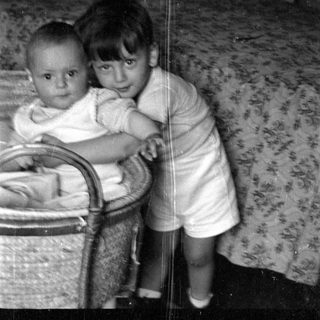 Two young children by a wicker bassinet.