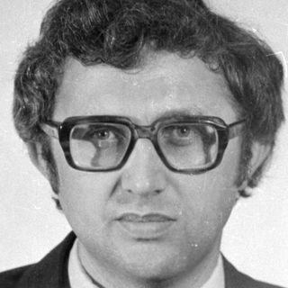 Studio portrait of a man in a suit and glasses.