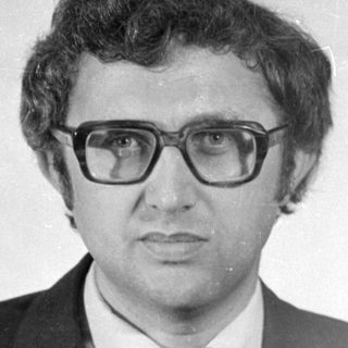 Studio portrait of a man in a suit and glasses.