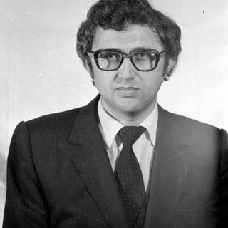 Studio portrait of a man in a suit and glasses.
