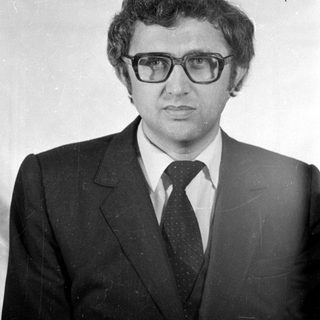 Studio portrait of a man in a suit and glasses.