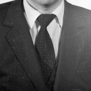 Studio portrait of a man in a suit and glasses.