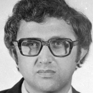 Studio portrait of a man in a suit and glasses.