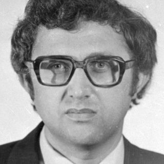 Studio portrait of a man in a suit and glasses.