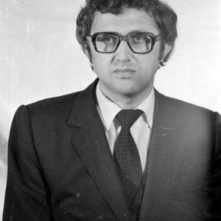 Studio portrait of a man in a suit and glasses.