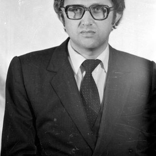 Studio portrait of a man in a suit and glasses.