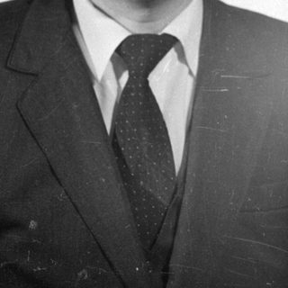 Studio portrait of a man in a suit and glasses.