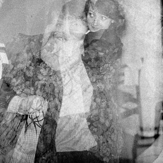 Double-exposure portrait of two people in dark clothing.
