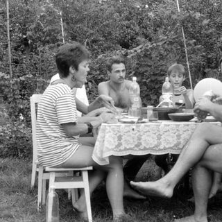 Four people gathered around a table in a garden.