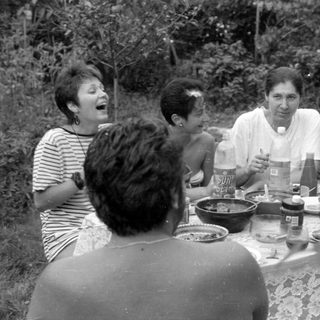 Group of people dining outdoors in a garden.