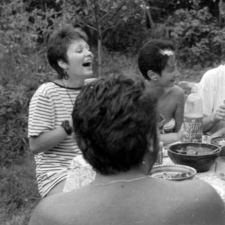 Group of people dining outdoors in a garden.