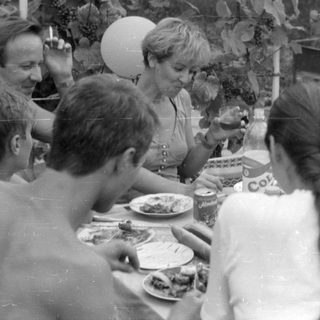 Outdoor gathering with people around a dining table.