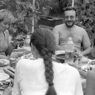 Outdoor gathering with people around a dining table.