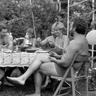 Group of people dining outdoors in a garden.