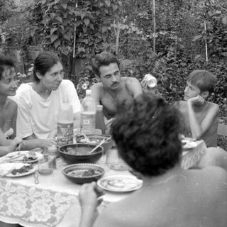 Group of people dining outdoors in a garden.