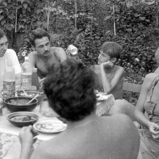 Group of people dining outdoors in a garden.