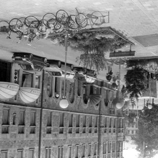 Upside-down street scene with stone building and bicycles.