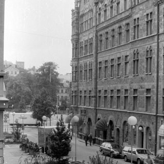 City street with stone building and parked bicycles.