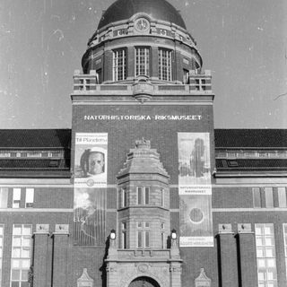 Exterior of Naturhistoriska Riksmuseet with banners and visitors.