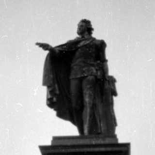 Man sitting at the base of a large statue.