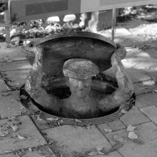 Sculpture of a man emerging from a manhole.