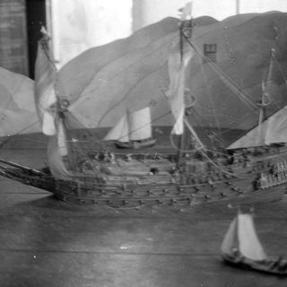 Model sailing ship and smaller boats on a surface.