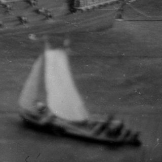 Model sailing ship and smaller boats on a surface.