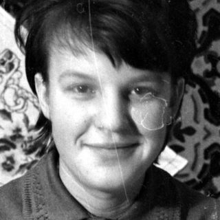 Person in dark jacket lying on patterned rug.