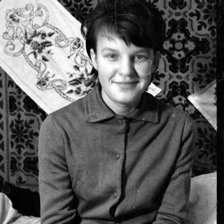 Person in dark jacket lying on patterned rug.