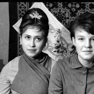 Two young women posing against a patterned backdrop.