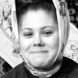Person in headscarf lying on patterned rug.