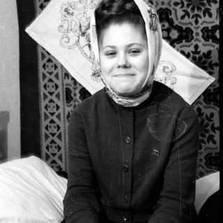 Person in headscarf lying on patterned rug.