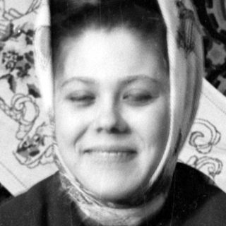 Woman in headscarf against patterned textile background.