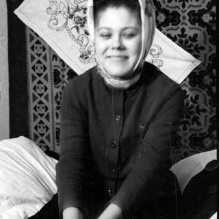 Woman in headscarf against patterned textile background.