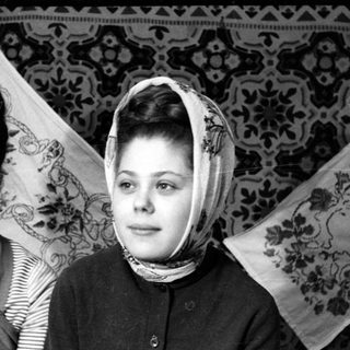 Two young women posing before patterned textiles.