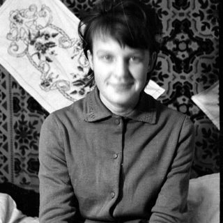 Person lying on a patterned rug and embroidery.