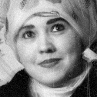 Person in headscarf lying on a patterned rug.