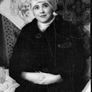 Person in headscarf lying on a patterned rug.